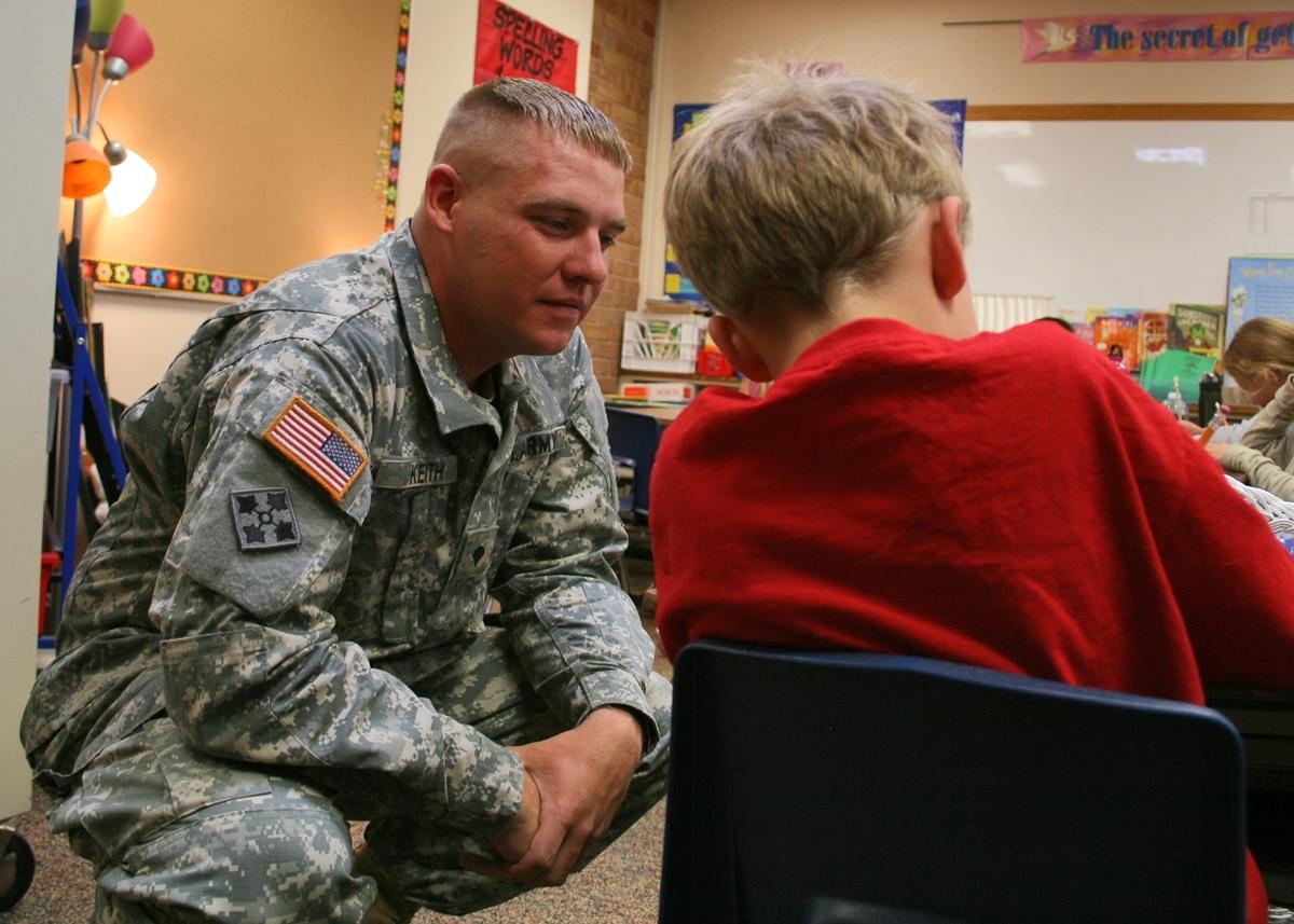 Spc. Bryan Keith, fire detection control specialist, Battery B, 3rd Battalion, 16th Field Artillery Regiment, 2nd Brigade Combat Team, 4th Infantry Division, helps a child with his reading work at Keller Elementary School  How your VA disability benefits can help pay for dependentsâ€™ education