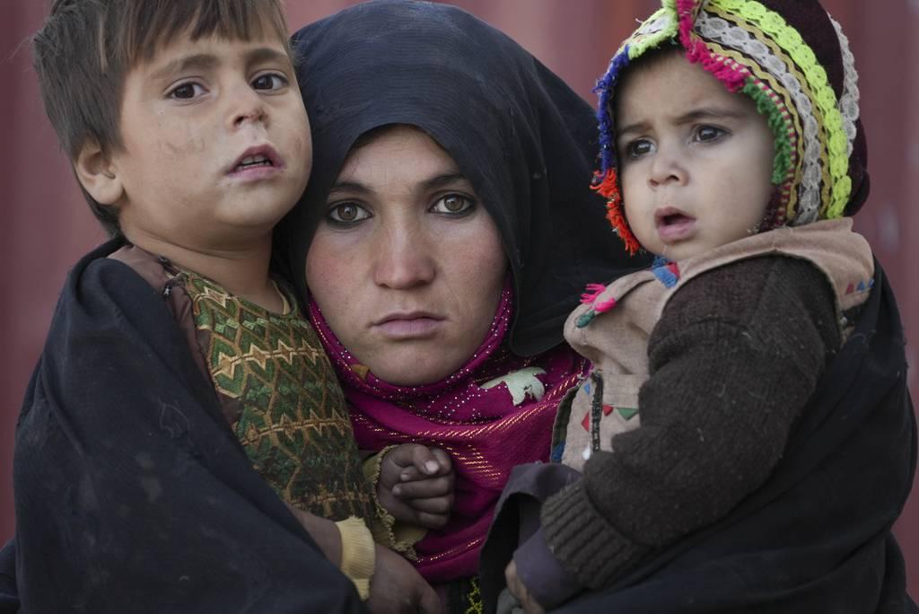 An Afghan woman holds her children as she waits for a consultation outside a makeshift clinic at a sprawling settlement of mud brick huts housing those displaced by war and drought near Herat, Afghanistan, Dec. 16, 2021. ( Afghan evacuation flights to resume with streamlined process