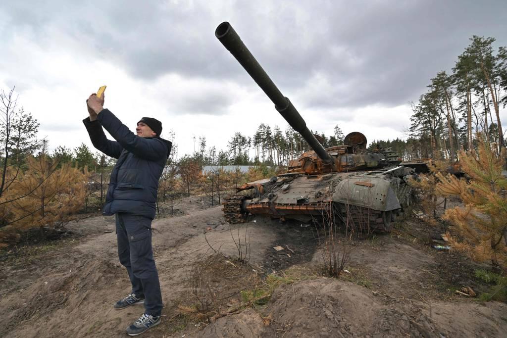 Thumbnail: A man takes a selfie as he stands in front of a destroyed Russian tank in the village of Andriivka, in the Kyiv region, on April 17, 2022. (Sergei Supinski/AFP via Getty Images)